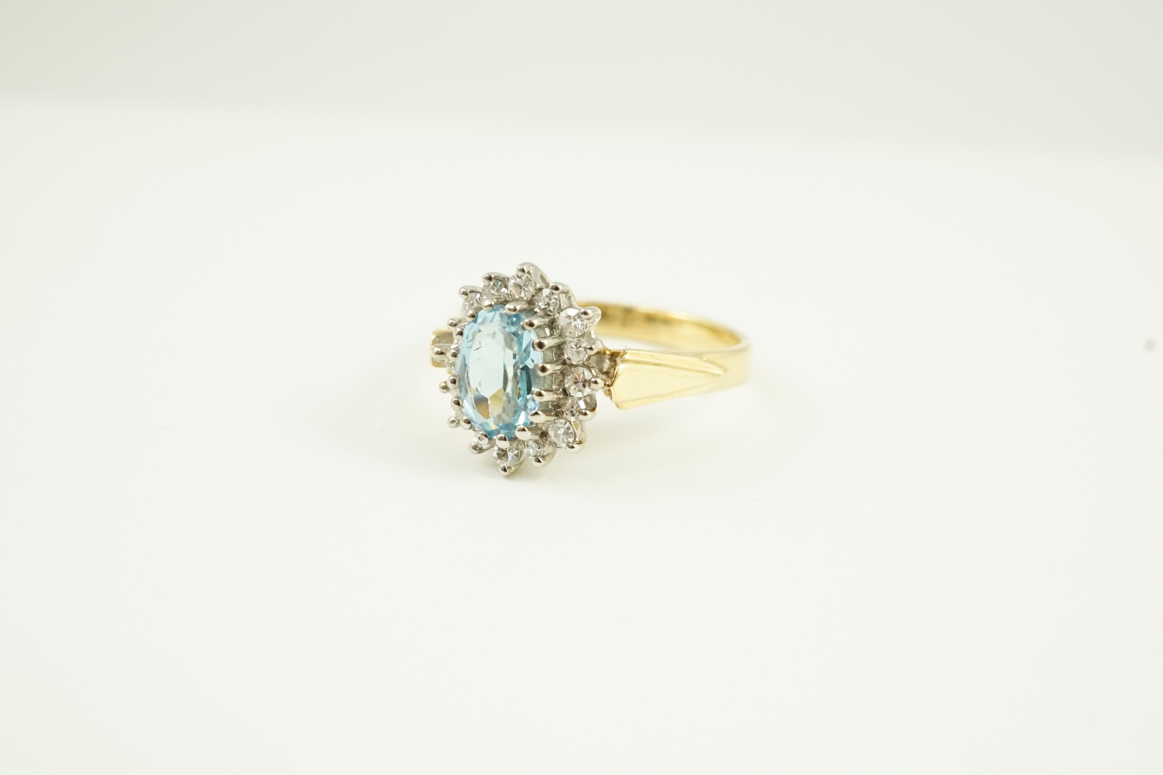 A modern 18ct gold aquamarine and diamond set oval cluster ring, size K/L, gross weight 3.8 grams.